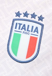 Έμβλημα ποδοσφαιρικής ομάδας Ιταλίας με τα χρώματα της ιταλικής σημαίας και τέσσερα αστέρια κεντημένα σε λευκό υφασμάτινο φόντο με υφή.