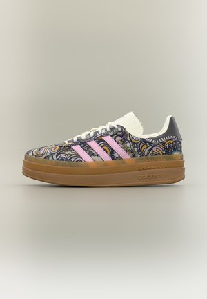 Sneakers Adidas à plateforme basse avec motif paisley, bandes roses, lacets blancs et semelle marron sur fond uni.