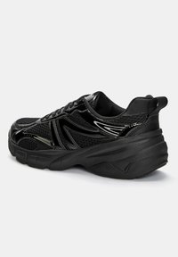 Pantofii sport negri cu un superior din plasă, tălpi texturate și accente lucioase. Au vârful rotunjit și o talpă intermediară cu amortizare.