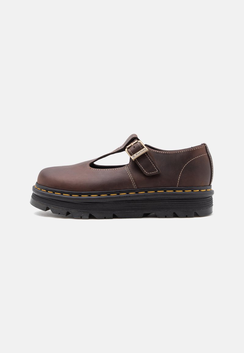 Chaussure Mary Jane en cuir marron foncé avec boucle métallique, coutures jaunes et semelle épaisse noire avec crampons profonds, vue latérale sur fond blanc.