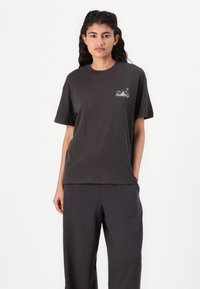 T-shirt cotone nero con maniche corte, caratterizzato da un piccolo ricamo sul lato sinistro del petto. Abbinato a pantaloni scuri, ampi e dalle texture interessanti.