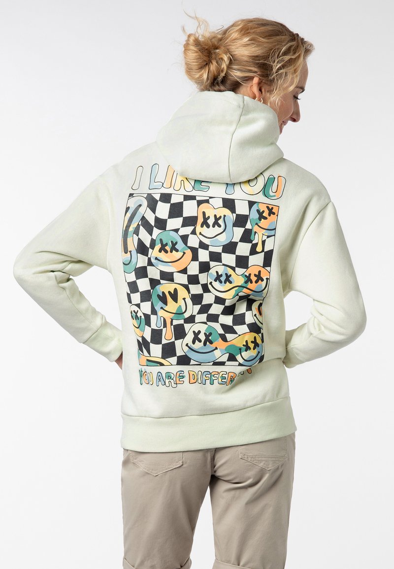 Lichtgroene hoodie met een grafische print op de achterkant die kleurrijke abstracte gezichten op een dambordachtergrond en tekst toont.
