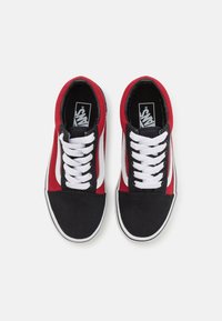 Red and black canvas sneakers with white laces, featuring a white side stripe and a black toe cap. Rubber sole and padded collar.