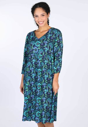Blumenkleid in dunklem Marineblau mit grünen und blauen botanischen Mustern. Verfügt über einen V-Ausschnitt und Dreiviertelärmel. Weicher, fließender Stoff.