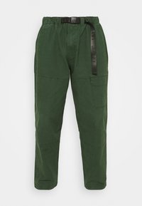 Pantaloni casual verdi con vita elastica, cintura nera con marchio, tasca laterale e cuciture rinforzate sulle ginocchia, vista frontale su sfondo bianco.