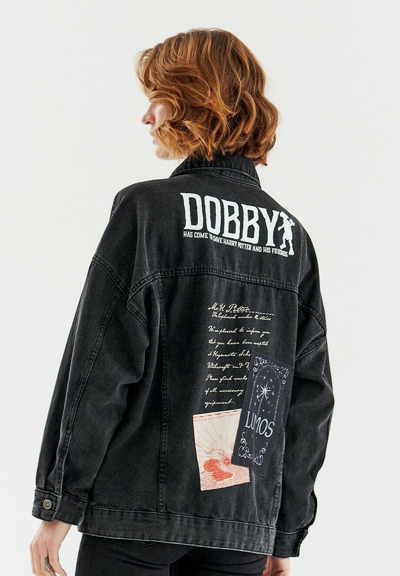 Czarna dżinsowa kurtka z nadrukami tekstowymi i graficznymi na plecach, w tym logo "DOBBY" oraz ilustracje przypominające karty i odręczne notatki.
