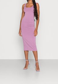 Robe midi violet ajustée avec un décolleté rond et des bretelles de type tank, fabriquée dans un tissu lisse. Assortie à des sandales à talons transparents.