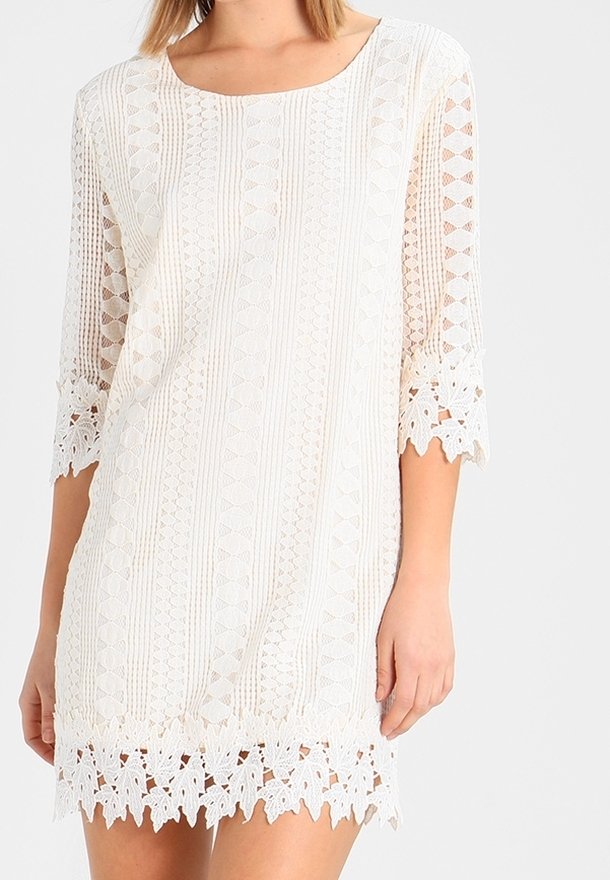 Robe en dentelle blanche avec des manches courtes et évasées. Présente un motif texturé et une bordure en dentelle florale à l'ourlet et aux manches pour une touche de détail supplémentaire.