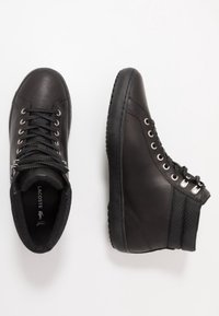 Czarne sneakersy za kostkę z fakturowaną skórzaną cholewką, okrągłym noskiem, sznurowaniem z przodu, srebrnymi oczkami i gumową podeszwą. Gładkie i trwałe materiały.