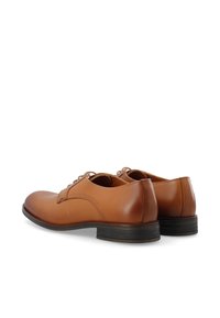 Chaussures habillées en cuir marron avec une texture lisse, bout arrondi et laçage. Talon en caoutchouc noir bas avec un profil minimal. Design épuré et simple.