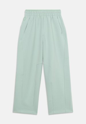 Pantalon ample vert clair avec taille élastique, poches latérales et un discret logo Nike sur la cuisse droite.