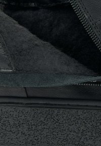 Czarne obuwie z gładkiej skóry i miękkim, teksturowanym wnętrzem. Posiada detal w postaci zamka błyskawicznego oraz teksturowaną podeszwę zapewniającą przyczepność.