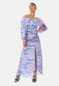 Two-piece set featuring an off-the-shoulder purple top with ruffles and a matching long skirt with a side slit, adorned with blue and pink patterns.
