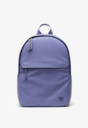 Sac à dos violet en matériau lisse, présentant une forme arrondie, une poche avant, deux compartiments zippés et une poignée supérieure.
