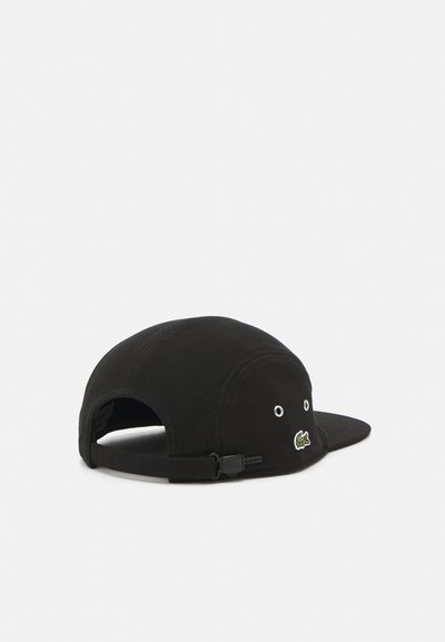 Casquette de baseball noire en tissu, avec une visière plate, une sangle ajustable à l'arrière et un petit logo de crocodile brodé à l'avant.
