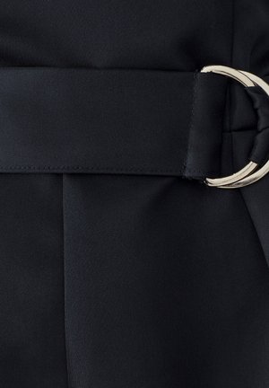 Melnas auduma josta ar lielu sudraba apaļu sprādzi, ar gludu tekstūru un plakanu apdari, integrēta struktūrētajā materiālā.