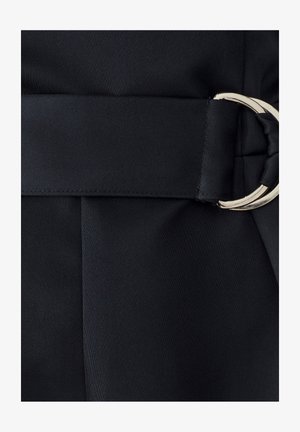 Černý látkový opasek s velkou stříbrnou kruhovou sponou, který se vyznačuje hladkým povrchem a plochým finišem, integrován do upraveného materiálu.