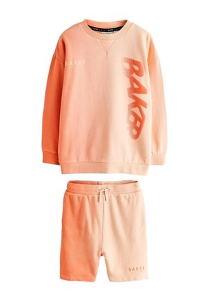 Ferskenfarvet langærmet sweatshirt med "BAKER" og shorts med snøre og teksten "BAKER" nederst til venstre.