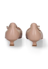 Nackte Leder-Kitten-Heels mit einem dekorativen goldnen Nieten-Design entlang der Kanten und einem kleinen Blockabsatz. Die Rückansicht zeigt Details des Knöchelriemens.