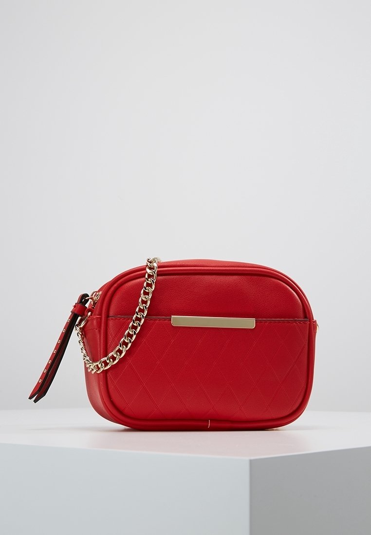 Punainen tekonahkainen olkalaukku, jossa tikattu kuvio, kullanväriset yksityiskohdat ja ketjuhihna. Laukussa on vetoketjullinen suljin ja litteä etutasku.