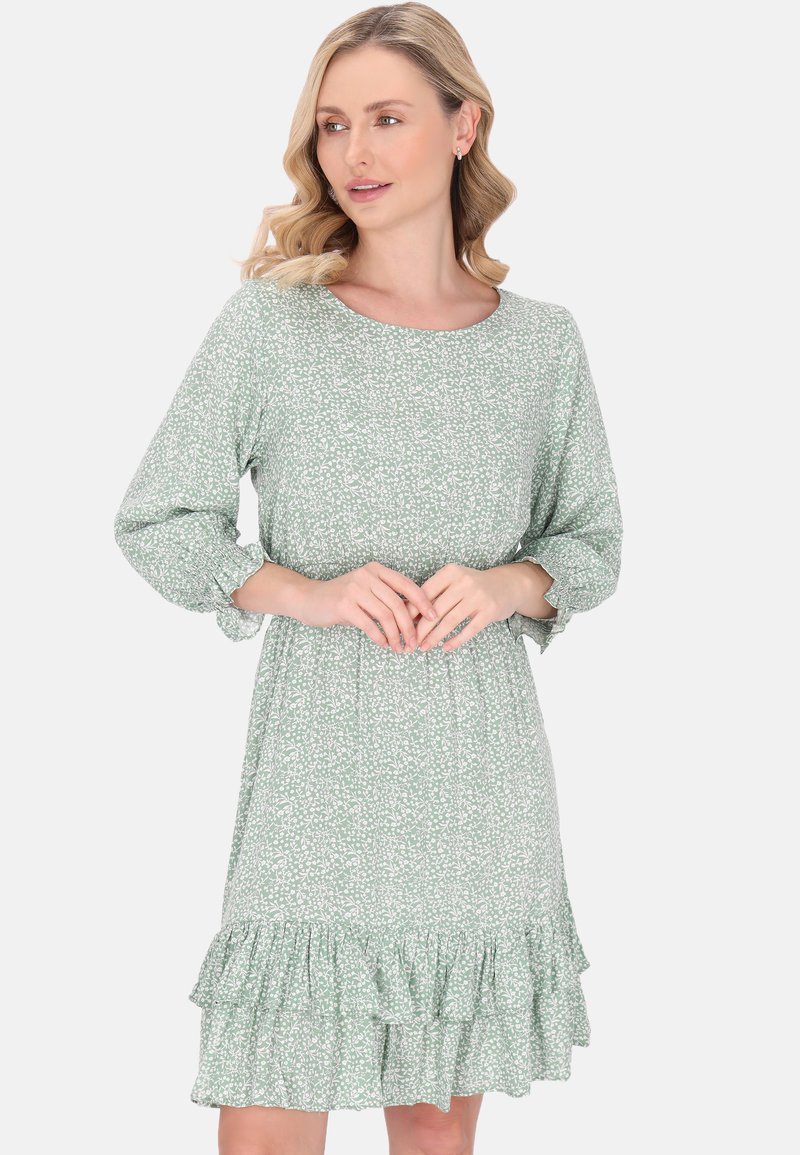 Vihreä kukkakuosiset mekko, jossa on kolmasosa hihat, pyöreä pääntie ja röyhelöreunus. Kevyt kangas, jossa on pehmeä rakenne.