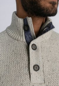 Pulover din tricot în gri deschis, cu un model texturat, având un guler rib pentru un aspect elegant, căptușeală albastră și trei închideri cu nasturi.