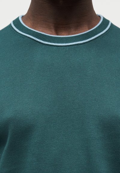 Σκούρο πράσινο πλεκτό πουλόβερ με ριμπ ύφανση στο στρογγυλό λαιμό και φωτεινή γαλάζια αντίθεση στο τελείωμα. Λεπτή υφή και εφαρμοστό σχέδιο.