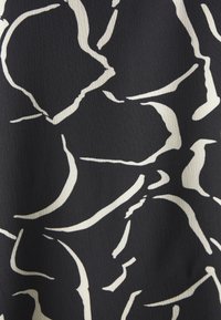Tissu noir avec un motif floral abstrait blanc comprenant de grandes formes de pétales courbés et de fines contours.