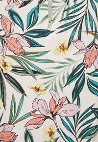 Tela floral con grandes flores rosas y amarillas acompañadas de hojas verdes sobre un fondo blanco. El diseño incluye un detallado trabajo de líneas y tonos variados.