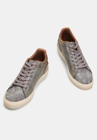 Grijze sneakers van suede en leer met bruine accenten, rubberen zolen en platte veters. Voorzien van een ronde teen en een gestructureerd oppervlak.