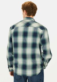 Geruite shirt in groen en marineblauw, met een knoopsluiting bij de kraag, lange mouwen en een lichtgewicht stof met een gladde textuur.
