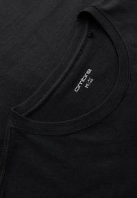 T-shirt noir à col rond montrant un gros plan du col et de l'étiquette intérieure avec le nom de la marque "ombre" et la taille "M / 48" en texte blanc.