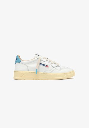 Sneaker in pelle bianca con suola beige, dettaglio blu sul tallone, lacci beige e piccolo logo con bandiera americana sul lato.