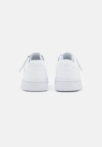 Sneaker bianche con tomaia in pelle liscia, lacci piatti e colli imbottiti. Presentano una punta arrotondata e una suola in gomma testurizzata.