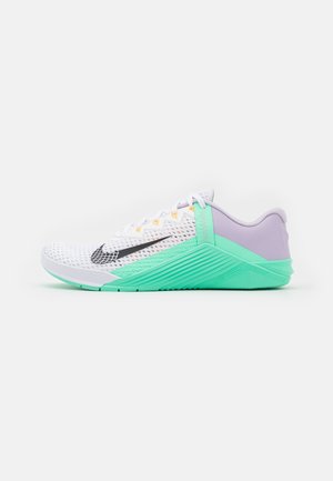 Hvid mesh sportssko med mintgrøn sål og hælstøtte, sort Nike-swoosh og lavendel hælkappe, set fra siden.