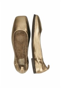 Ballerine metalliche dorate con una morbida fodera in pelliccia, punta quadrata e bordi elasticizzati per una vestibilità aderente. La suola è piatta e realizzata in materiale scuro.