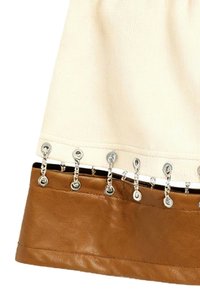 Tejido crema con ojales plateados y eslabones de cadena conectando a una banda de cuero marrón en el borde de una prenda.