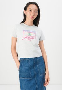 Svetlošedé bavlnené tričko s okrúhlym výstrihom, s multicolor potlačou loga a textom "tommy Jeans 1985 Založené v New Yorku".