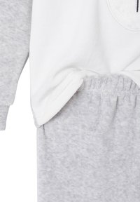 Gray fleece pajama set featuring a white top with a soft texture and a rounded hem; pants are also gray with an elastic waistband.