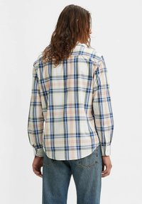 Katoenen geruite shirt met blauwe, groene en rode lijnen op een lichte achtergrond, lange mouwen en een gebogen zoom. De knoopsluitingen aan de mouwen zijn zichtbaar.