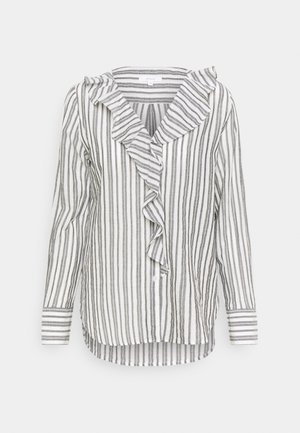 Blouse blanche à manches longues avec des rayures grises verticales, col en V à volants, fermeture boutonnée sur le devant et ourlet légèrement incurvé.