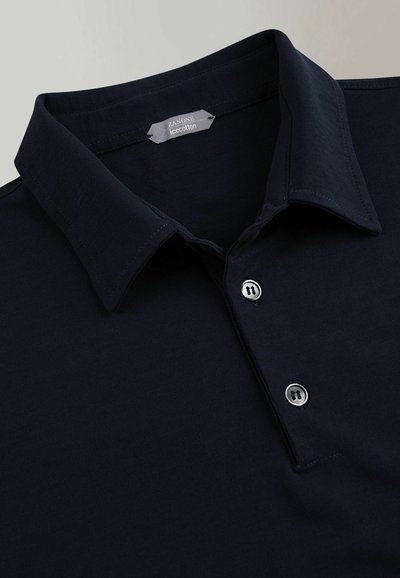 Polo navy de algodón suave con una tapeta de tres botones y un cuello plano y estructurado. Presenta costuras sutiles y botones en tono plateado.
