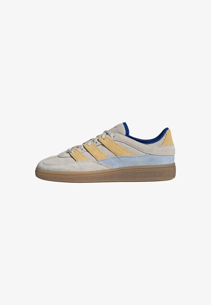Suede sneakers with a beige and light blue color scheme, featuring yellow stripes, a low-profile silhouette, and a rubber gum sole.