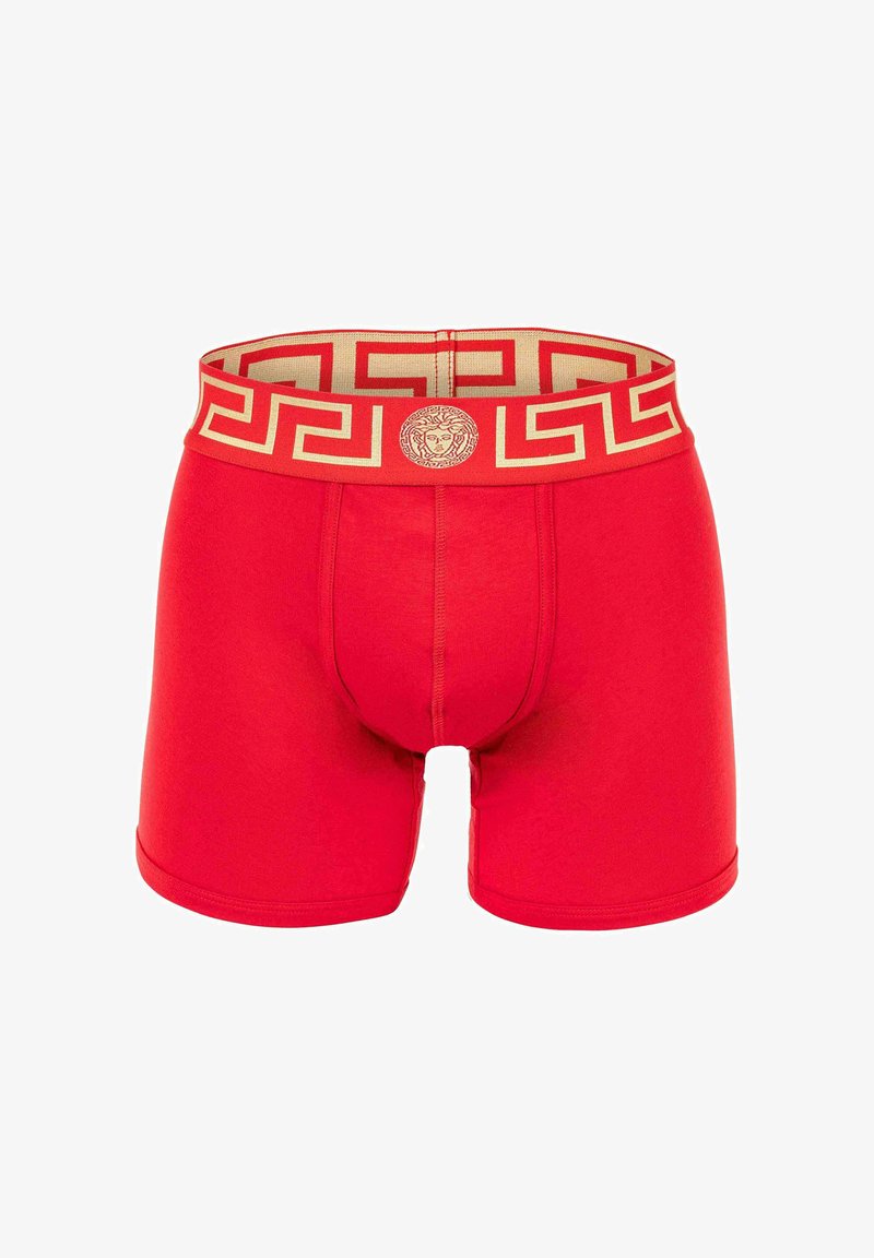 Red boxer shorts featuring a golden patterned waistband with a lion emblem. Soft material, snug fit, and mid-thigh length.