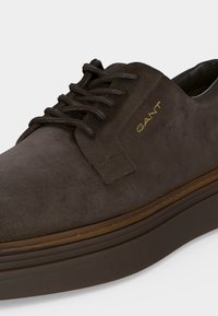 Σκούρο καφέ σουέντ casual παπούτσι με ταιριαστά κορδόνια, χοντρή σόλα και χρυσό λογότυπο "GANT" στην πλαϊνή πλευρά.