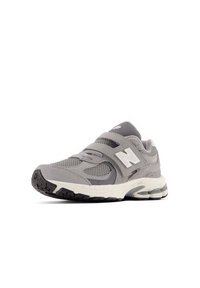 Chaussure de sport gris clair avec des matériaux en maille et en daim, dotée d'une sangle velcro, d'accents blancs et d'une semelle en caoutchouc texturée.
