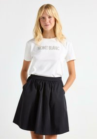 Vit t-shirt med kort ärm som har silverfärgad "MONT BLANC" text, ihop med en svart kjol med elastisk midja och fickor.