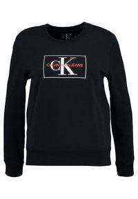 Czarna bluza z okrągłym dekoltem, wykonana z mieszanki bawełny, z prostokątnym białym logo z czerwonymi akcentami, ściągaczami przy rękawach i dolnym wykończeniu.