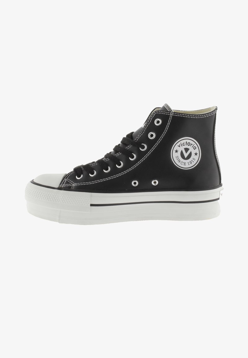 Zapatillas altas negras de material suave, con punta de goma blanca, suela y costuras en contraste, además de un detalle del logo en el costado.