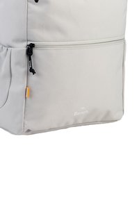 Sac à dos gris en tissu texturé, fermeture zippée sur le dessus, poche latérale en mesh et impression du logo ; dispose d'une languette contrastée et de coutures durables.
